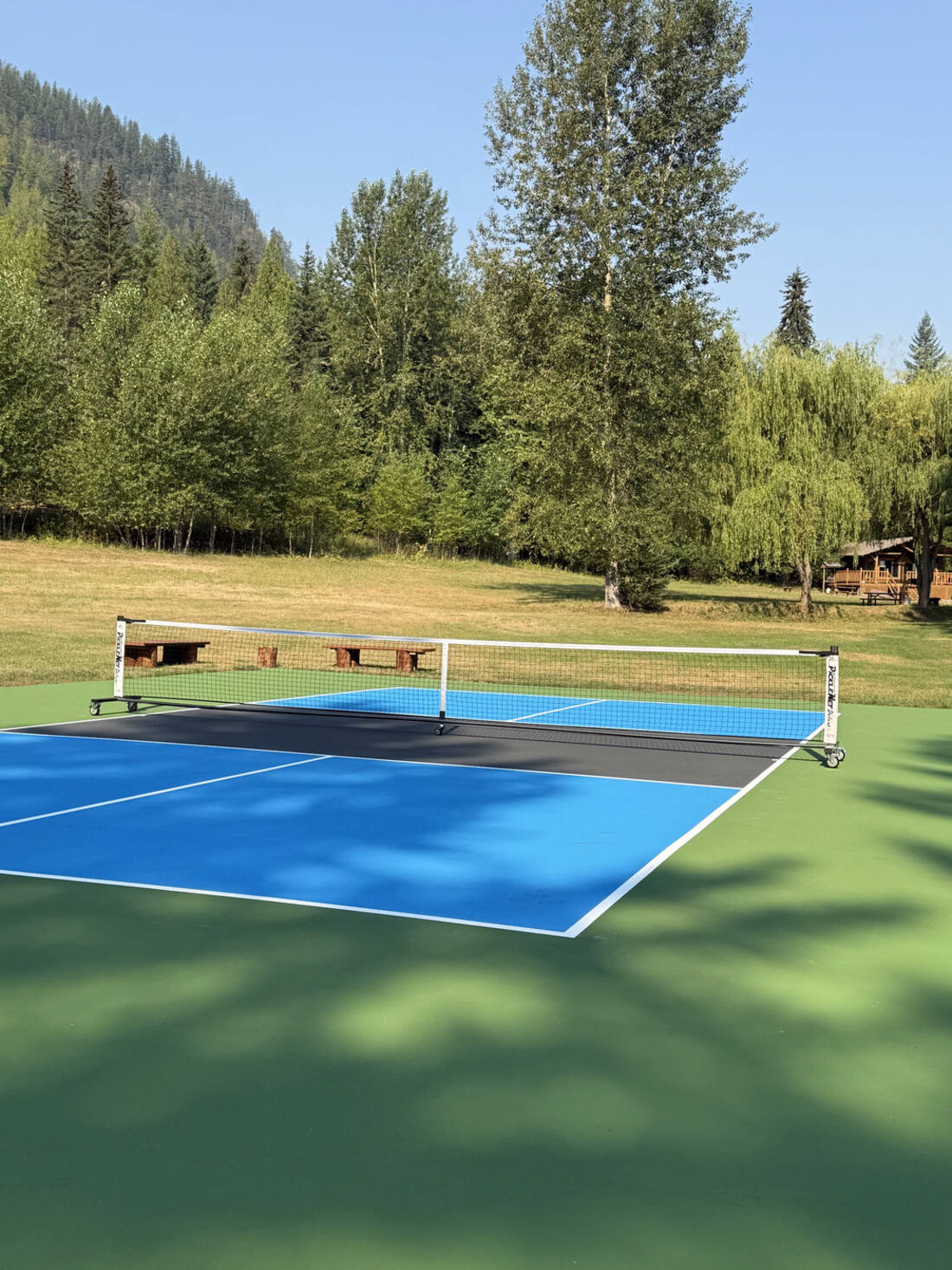 Close view of freshly painted pickleball court lines and net with Okanagan mountains behind