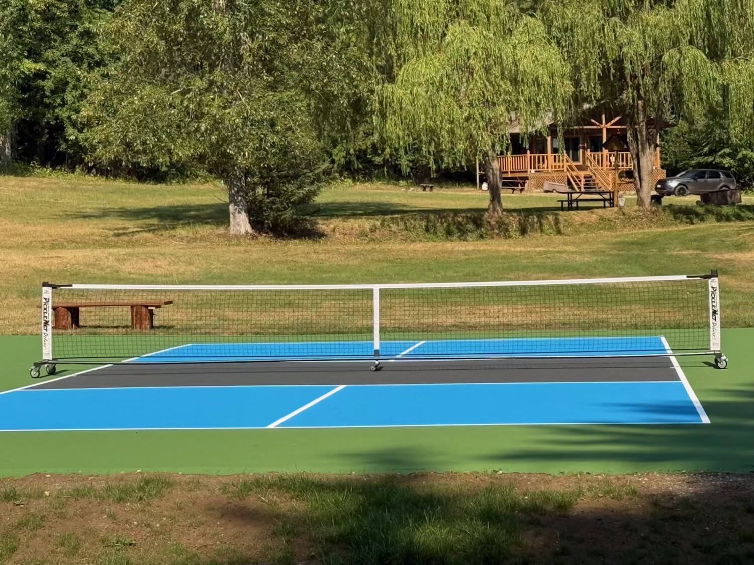 Completed backyard pickleball court painted blue and green with white regulation lines, Okanagan BC